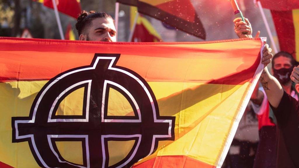 Un home portando unha bandeira española con simboloxía nazi durante unha manifestación da ultradereita en Barcelona. (Foto: Marti Segura Ramoneda / Europa Press)